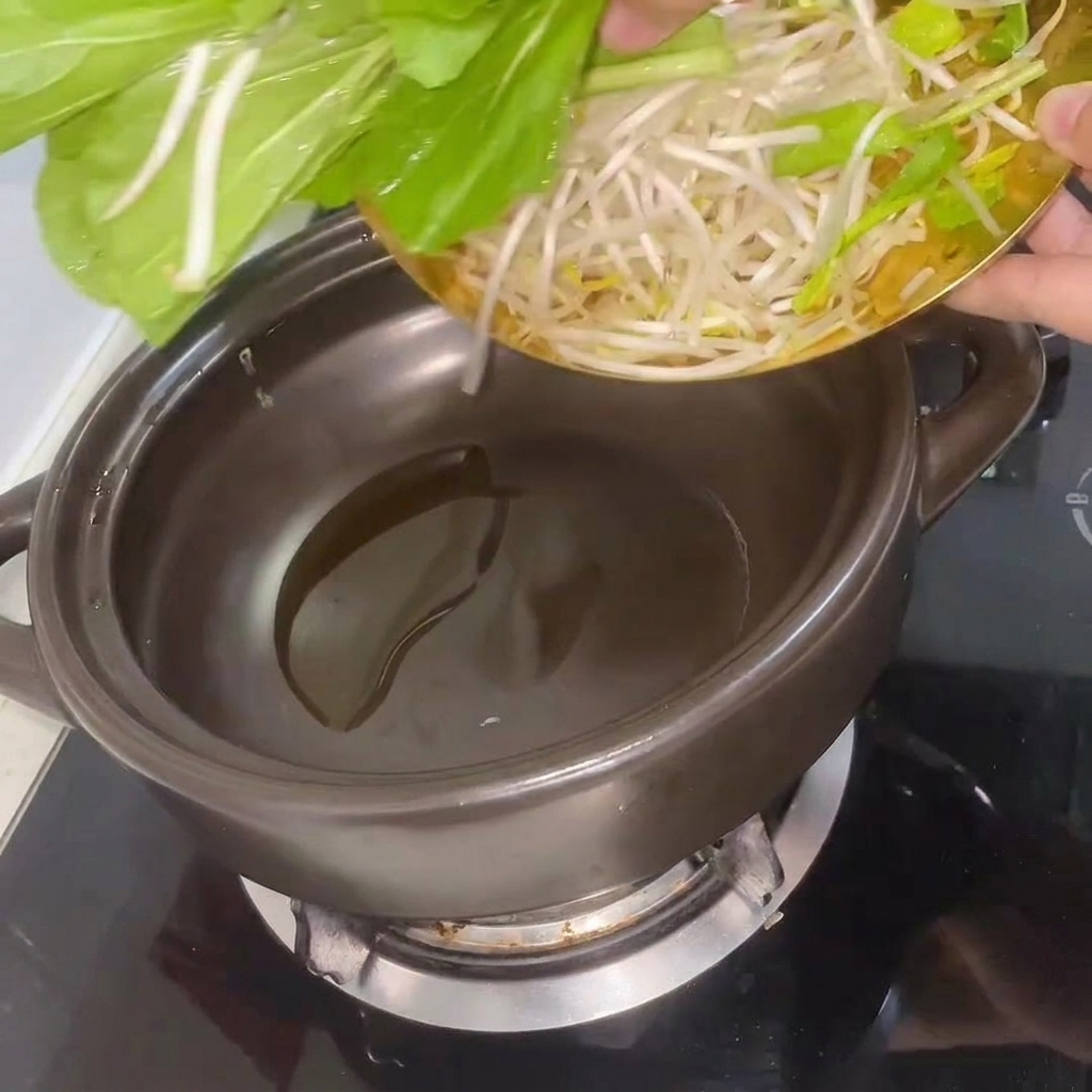熱した土鍋でチンゲン菜ともやしを炒めている様子