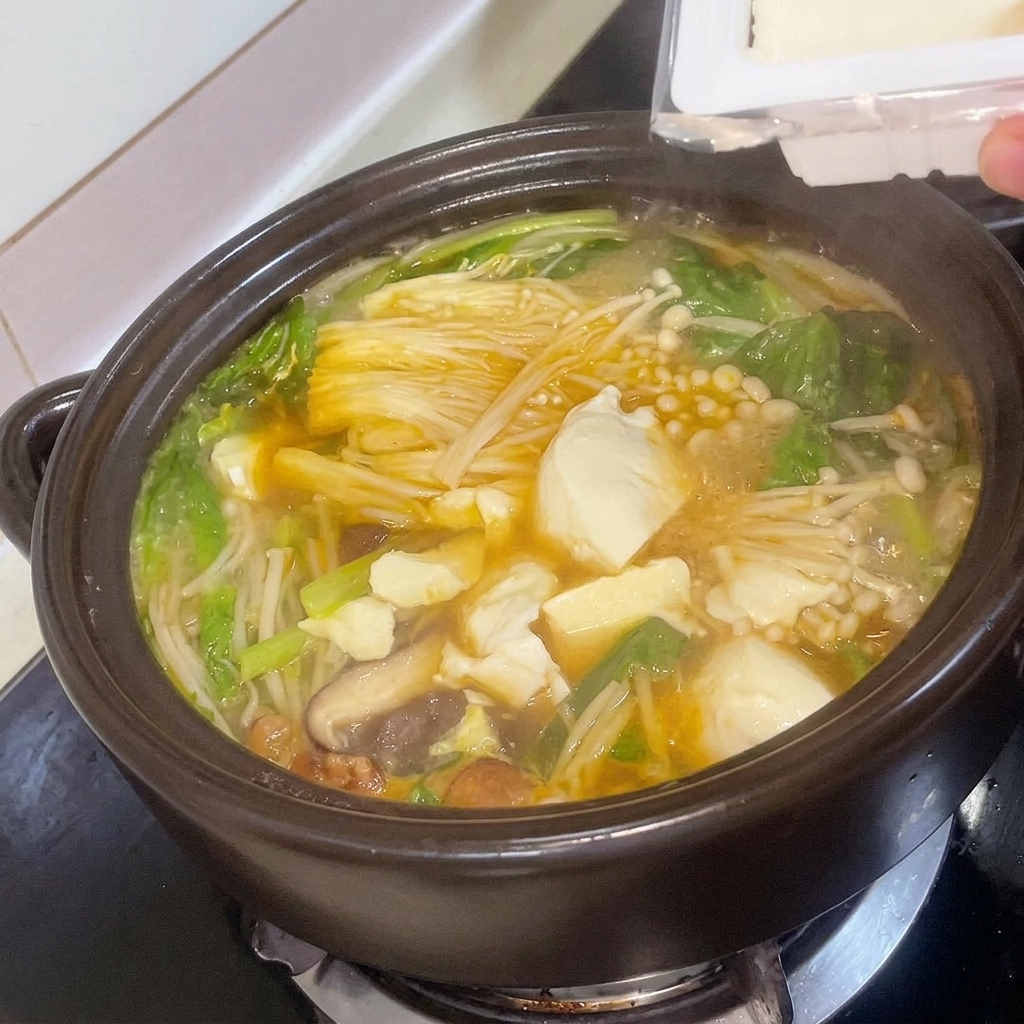 煮立っているチゲに角切り豆腐を入れている様子