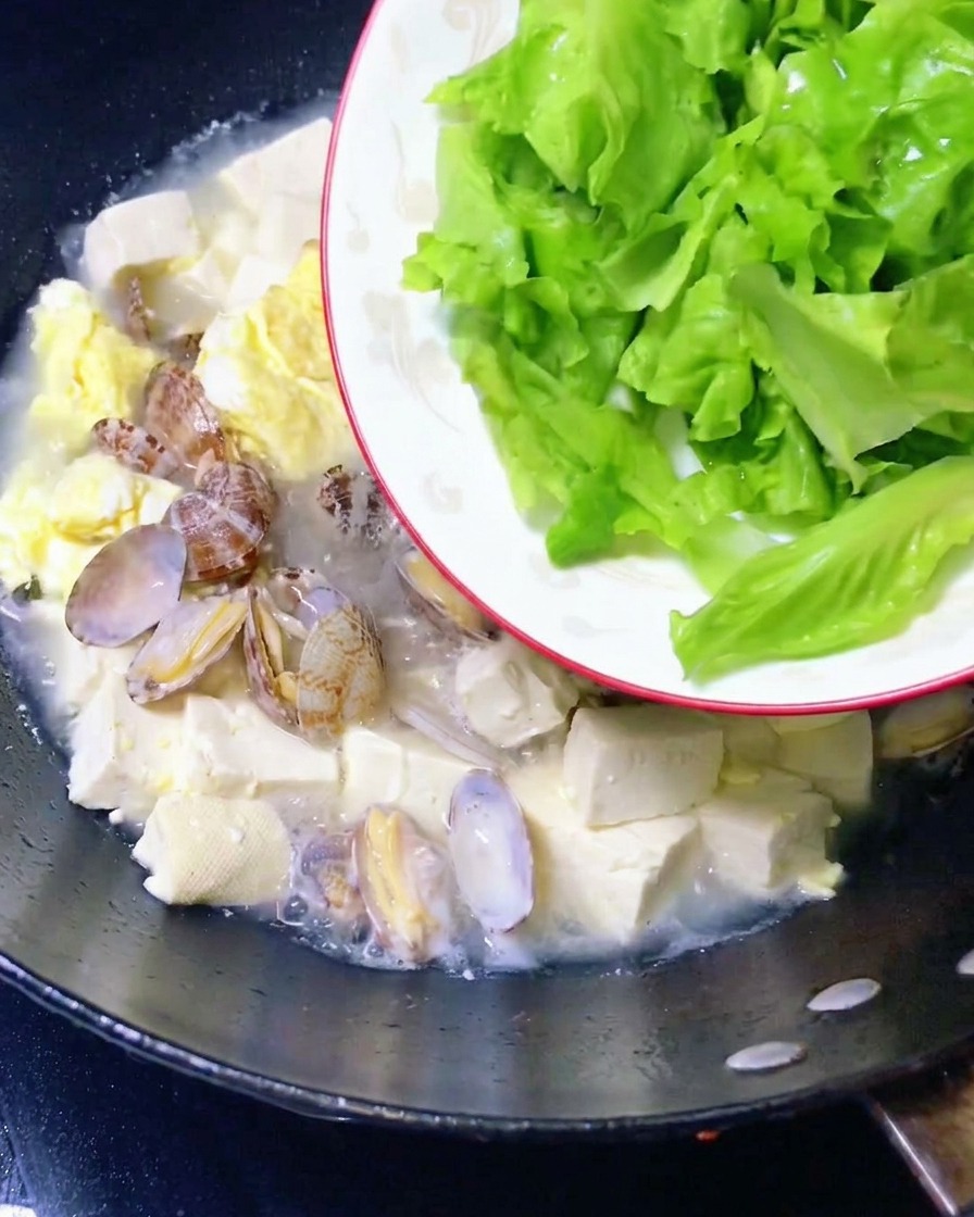 完成したアサリと豆腐のスープにレタスを入れている様子。