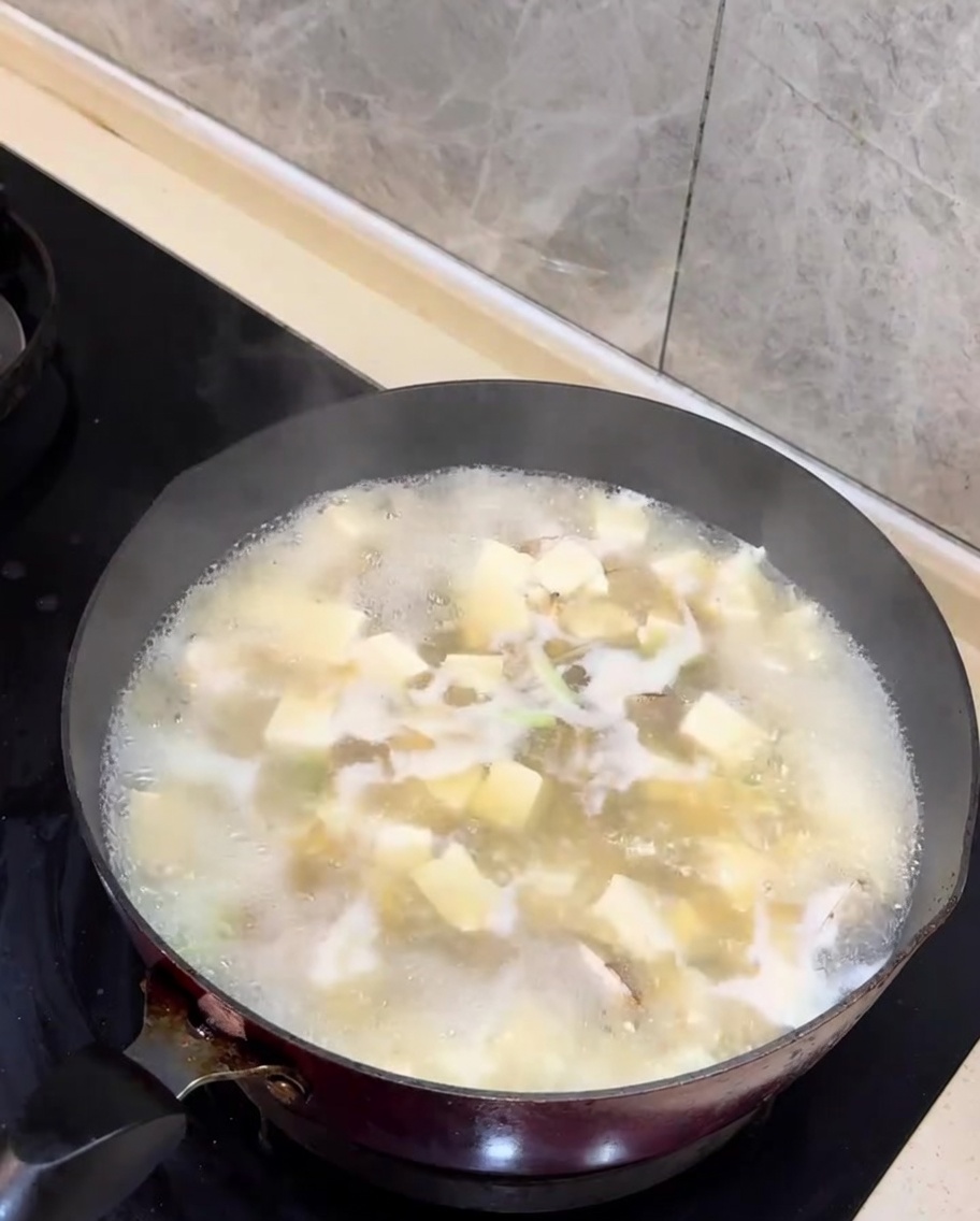 完成したあさりと豆腐のスープに刻んだ青ねぎが添えられている様子。