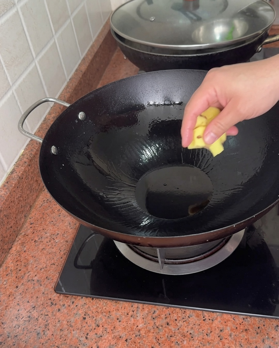 熱した油を入れた中華鍋に生姜を入れる様子。