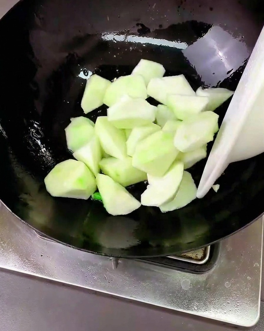 中華鍋の中でヘチマと薬味を一緒に炒めている様子。