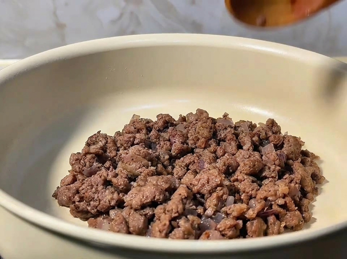 木べらでひき肉と玉ねぎを混ぜ合わせている様子