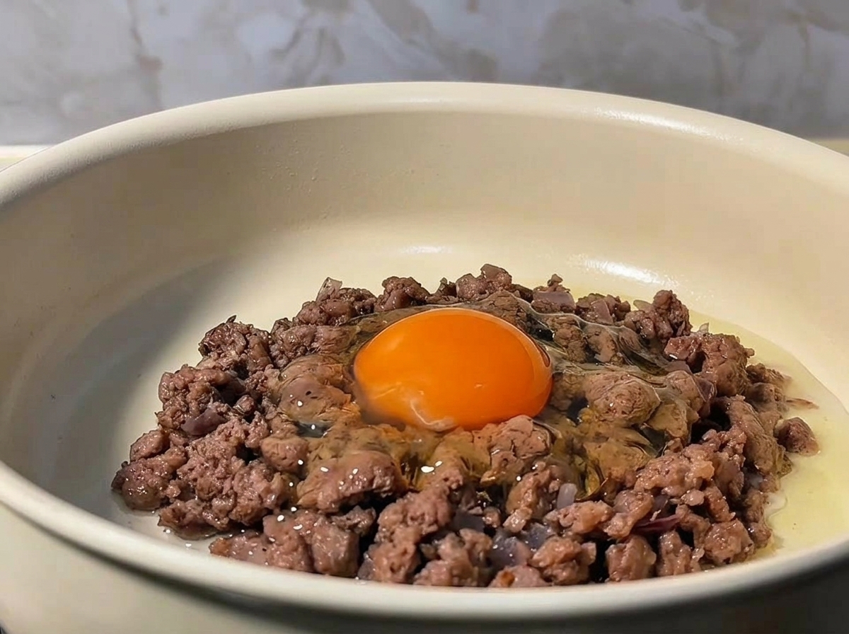 焼いたひき肉の中央に卵を落とした様子