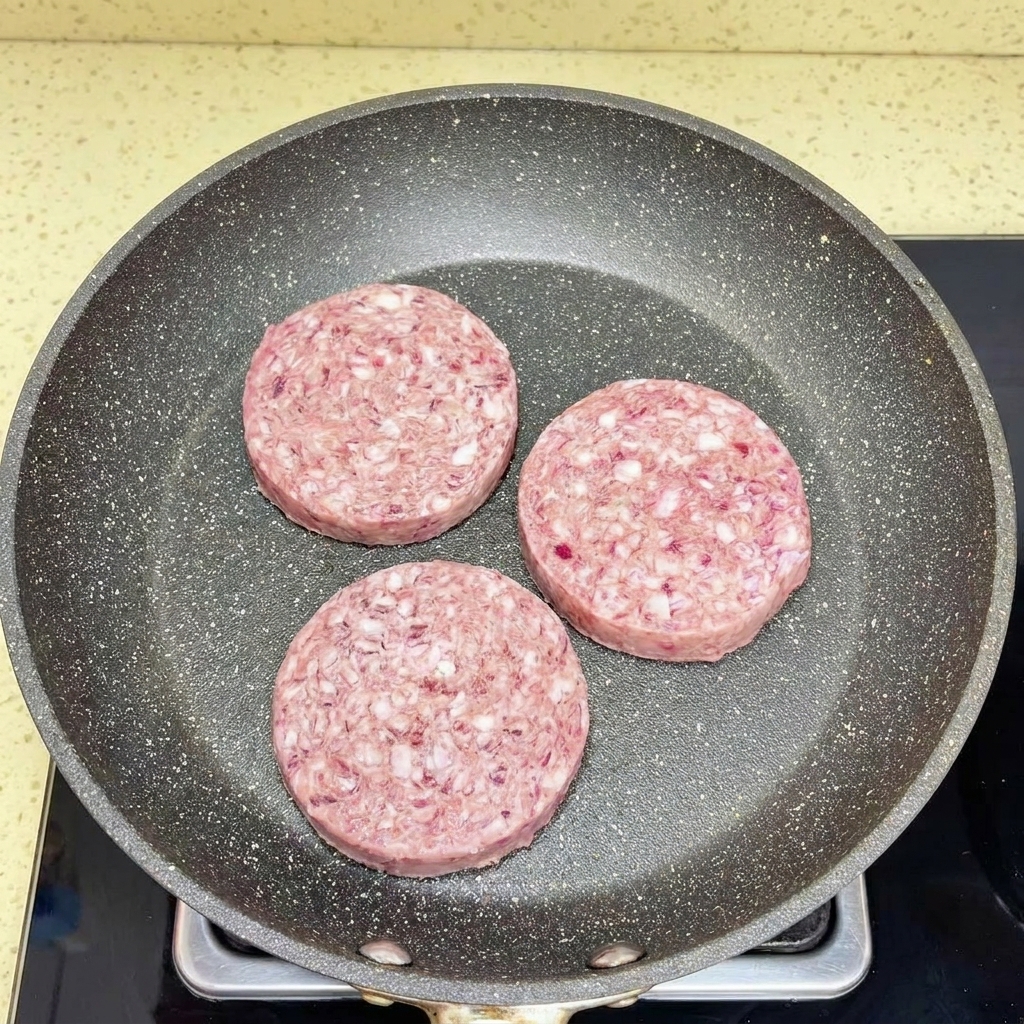 白いヘラを使って熱いフライパンの中で細かくほぐされている挽肉。