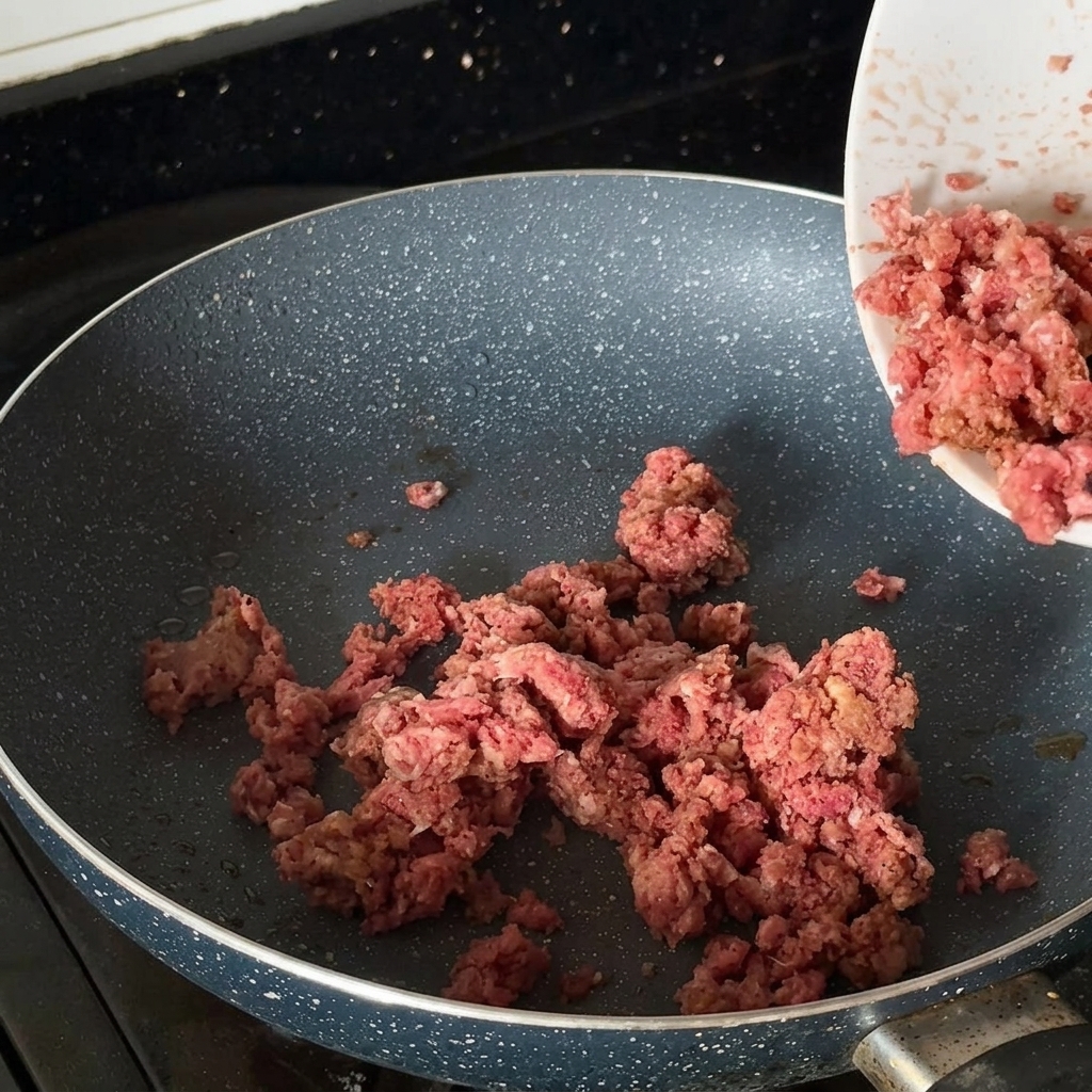 熱したフライパンで、味付けした牛ひき肉に焼き色をつけている様子。