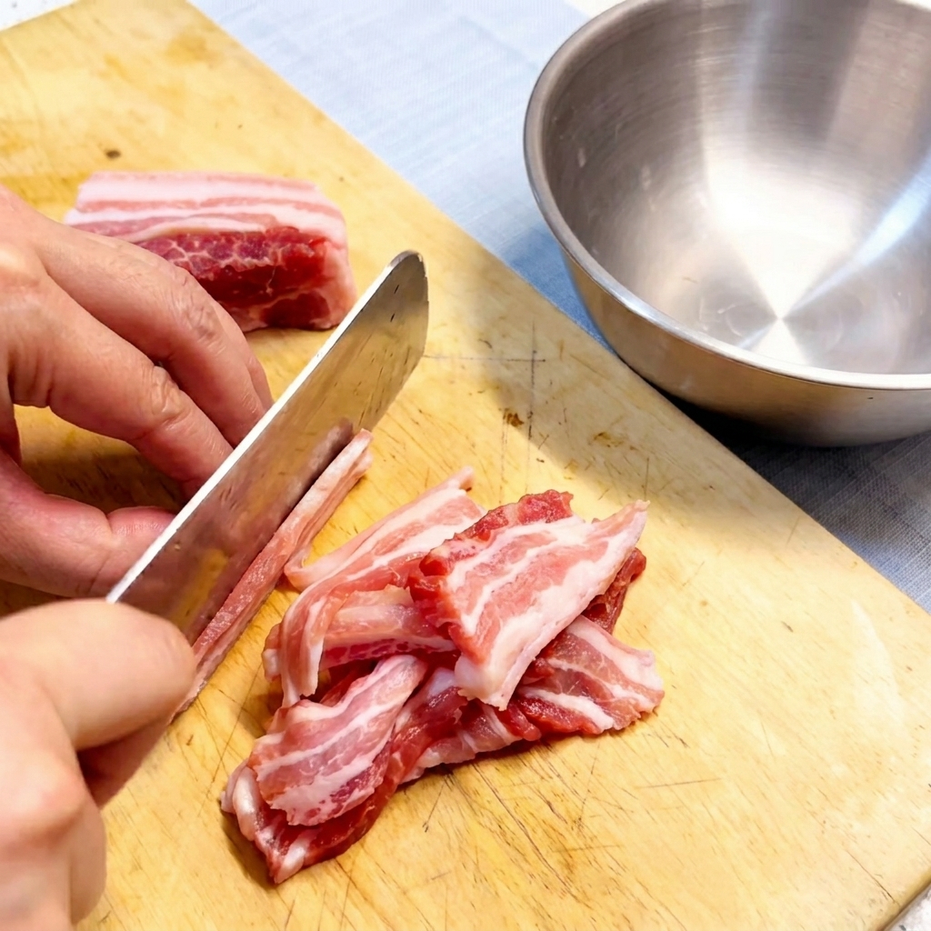 木製のまな板の上に、次に向けきれいに並べられた生の豚バラ肉のスライス。