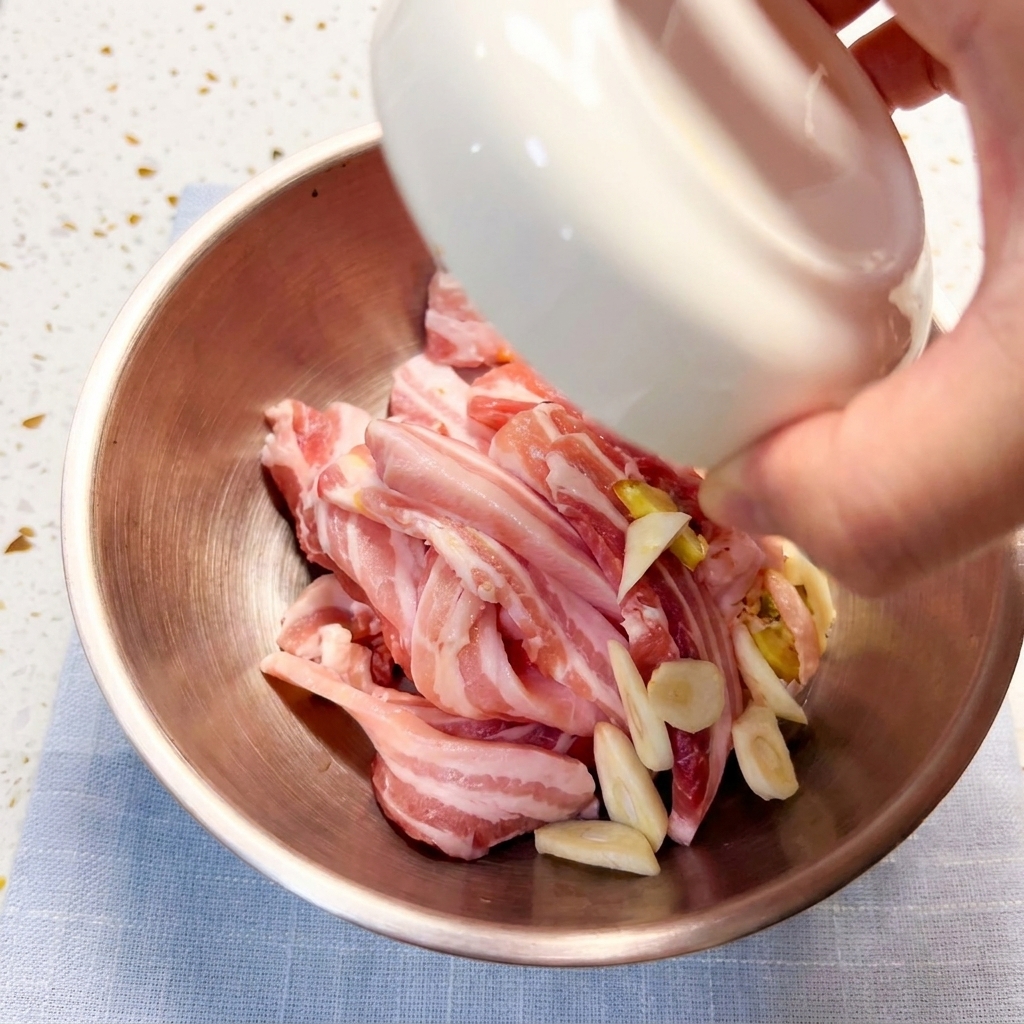 様々な調味料や材料と一緒にボウルの中でマリネされる豚バラ肉のスライス。