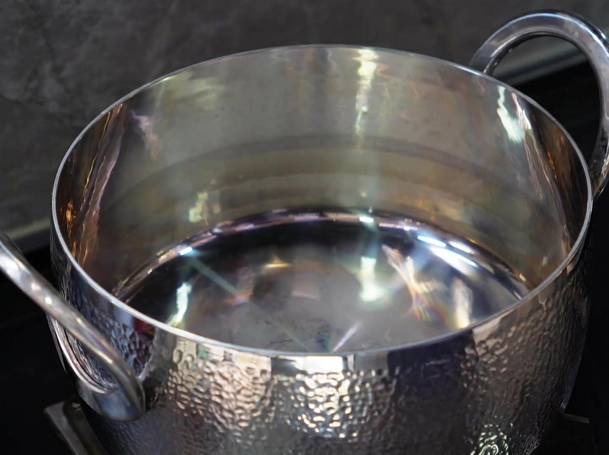 ステンレス鍋にサラダ油を注ぐ様子。