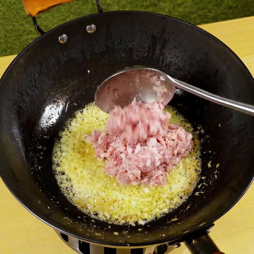 炒めた香味野菜と一緒に、フライパンで焼き色がつき始めた豚ひき肉。