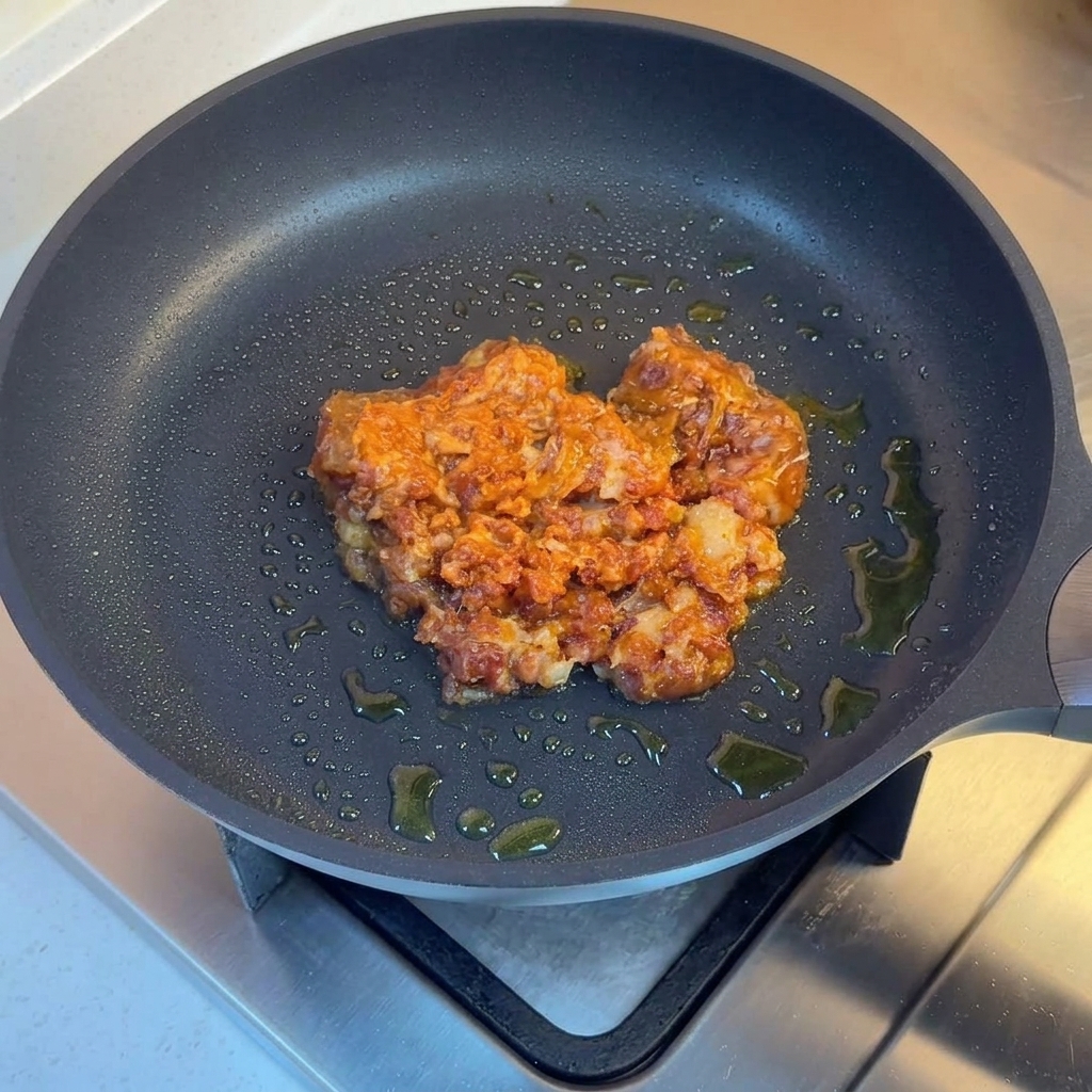 挽肉、玉ねぎ、ピーマン、赤唐辛子を一緒に炒めている様子。