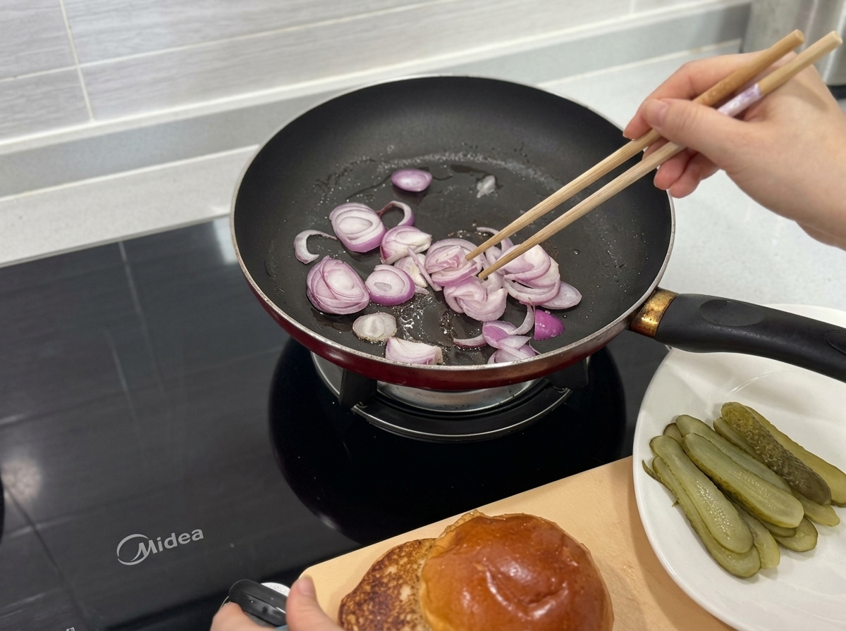 熱したフライパンで箸を使って炒められる赤玉ねぎのスライス。