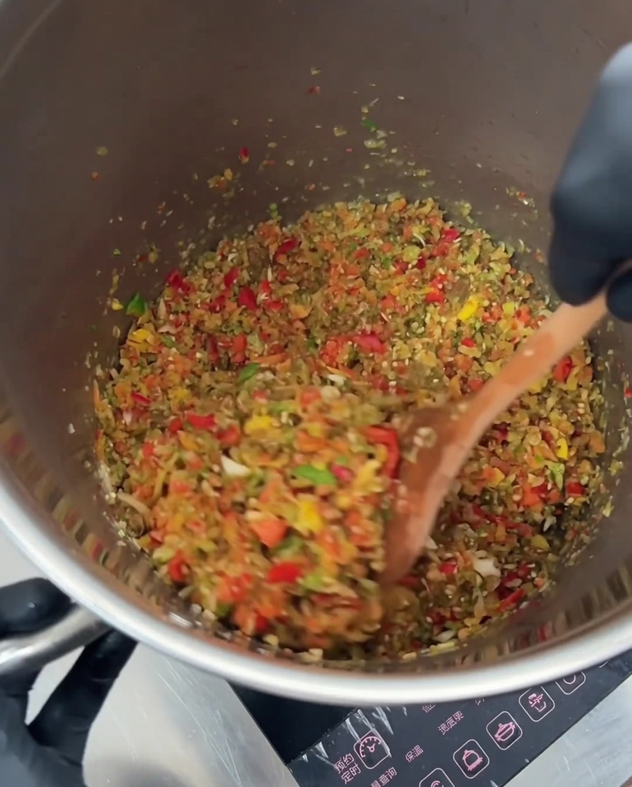 炒めた野菜の中に、レッドキドニービーンズと黄金色のコーンを混ぜ合わせている様子。