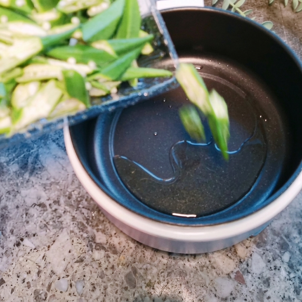 鍋の中で、少量の油でオクラを軽く炒めている様子。