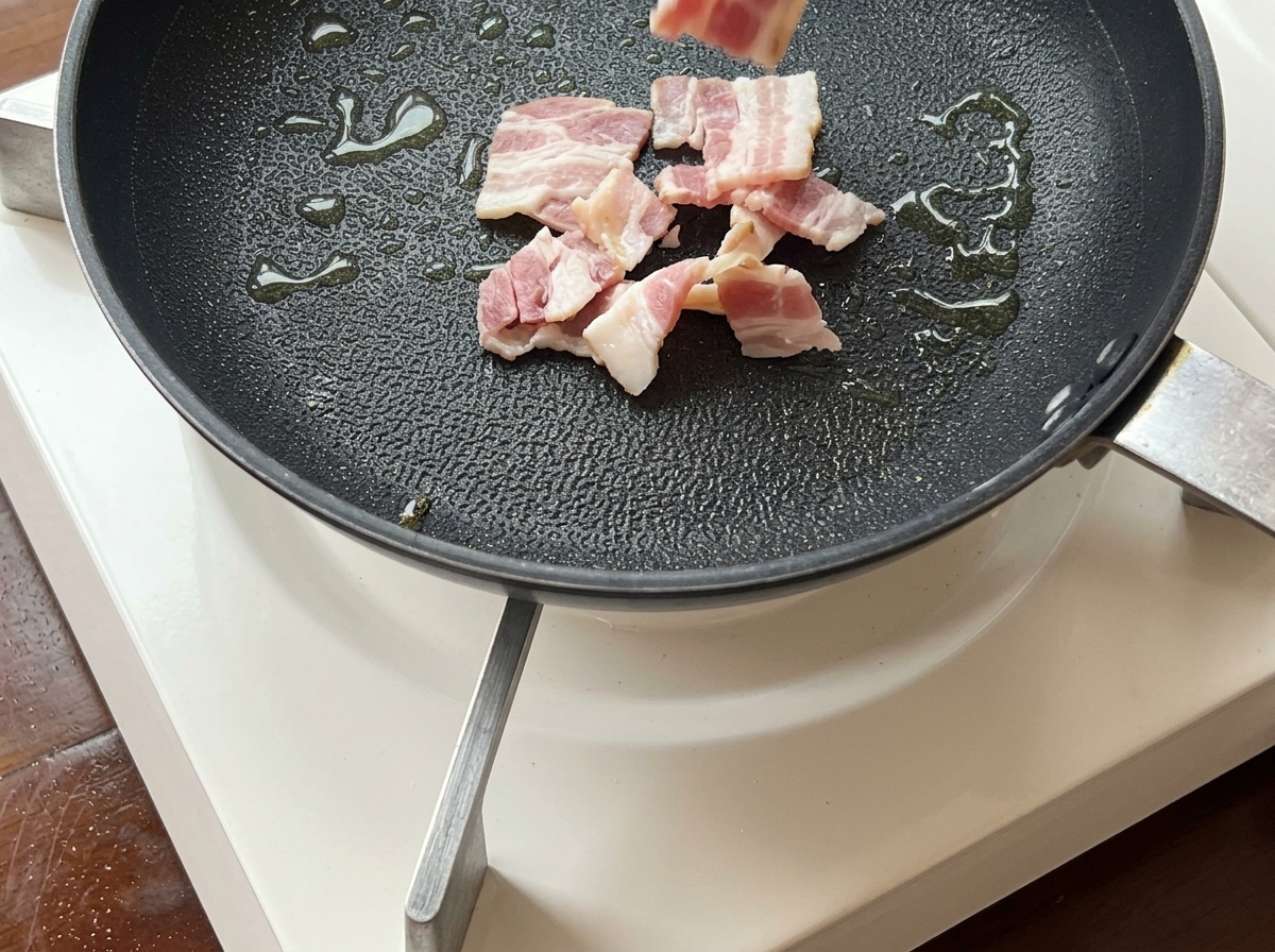 フライパンで黄金色にカリカリになるまで焼かれているベーコン。
