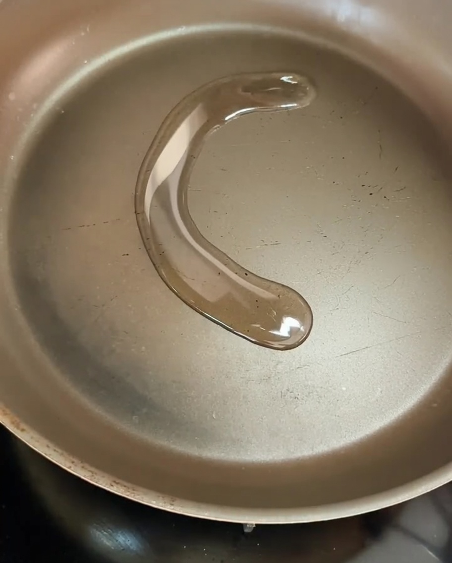 フライパンの中でオリーブオイルと共にスライスした玉ねぎが熱せられ、軽く焼き色がついている様子。