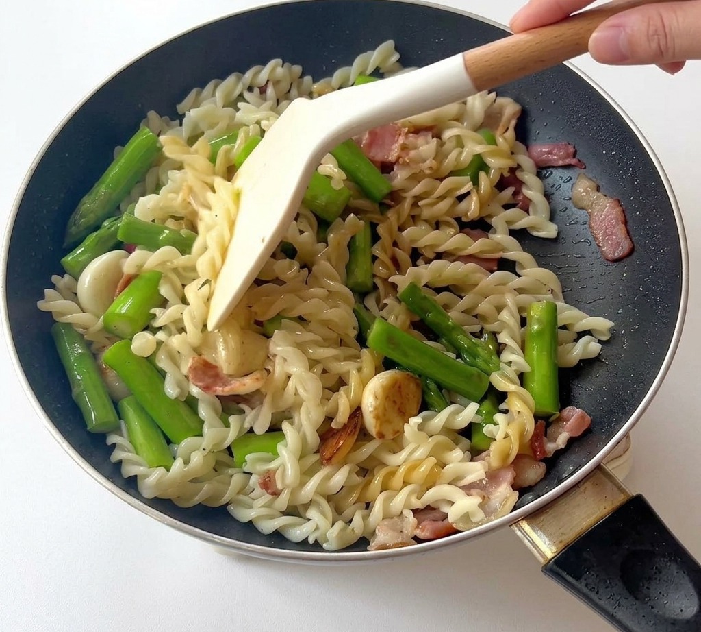 完成したパスタをフライパンで盛り付けている様子。