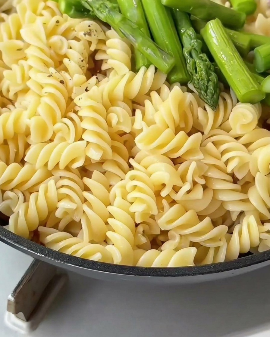 フライパンの中のパスタに粗挽き黒胡椒を振っている様子。