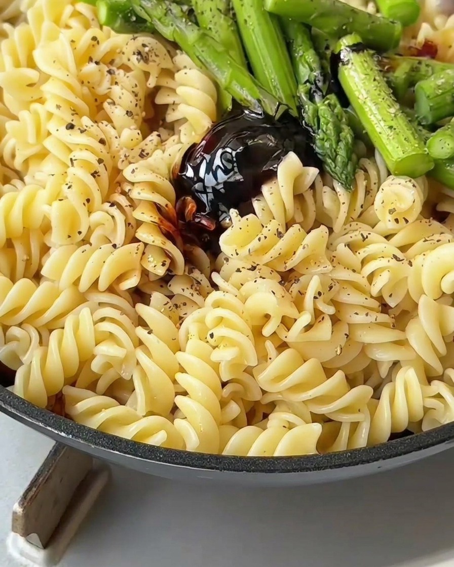 へらでパスタと具材をソースと絡めるように混ぜている様子。