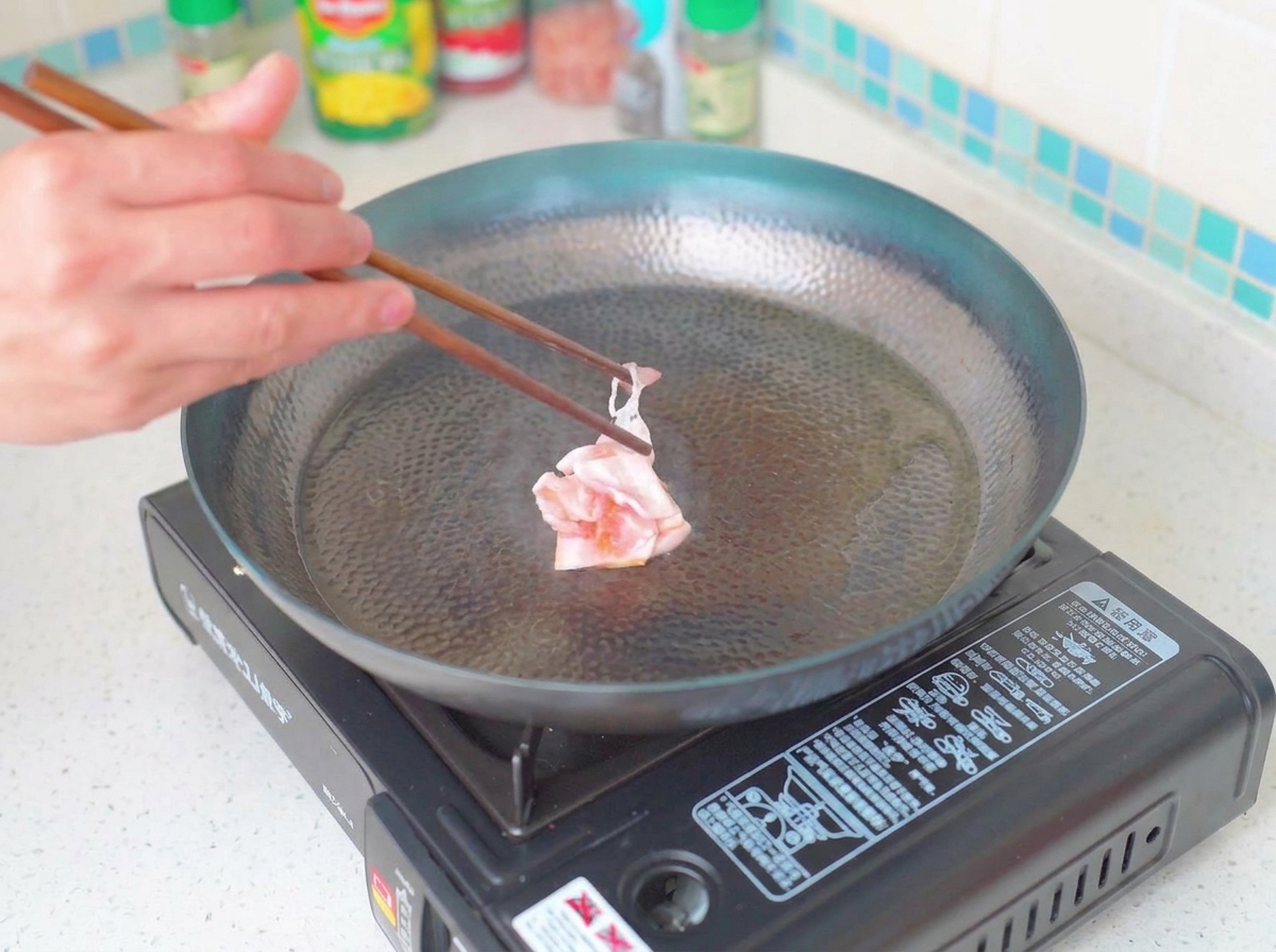 フライパンでベーコンがこんがりと焼けている様子。