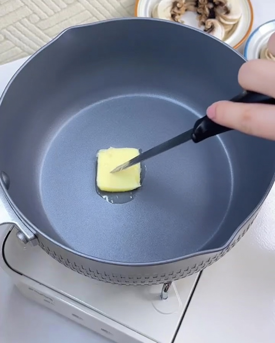 フライパンでバターを溶かし、スライスしたにんにくを炒めている様子。