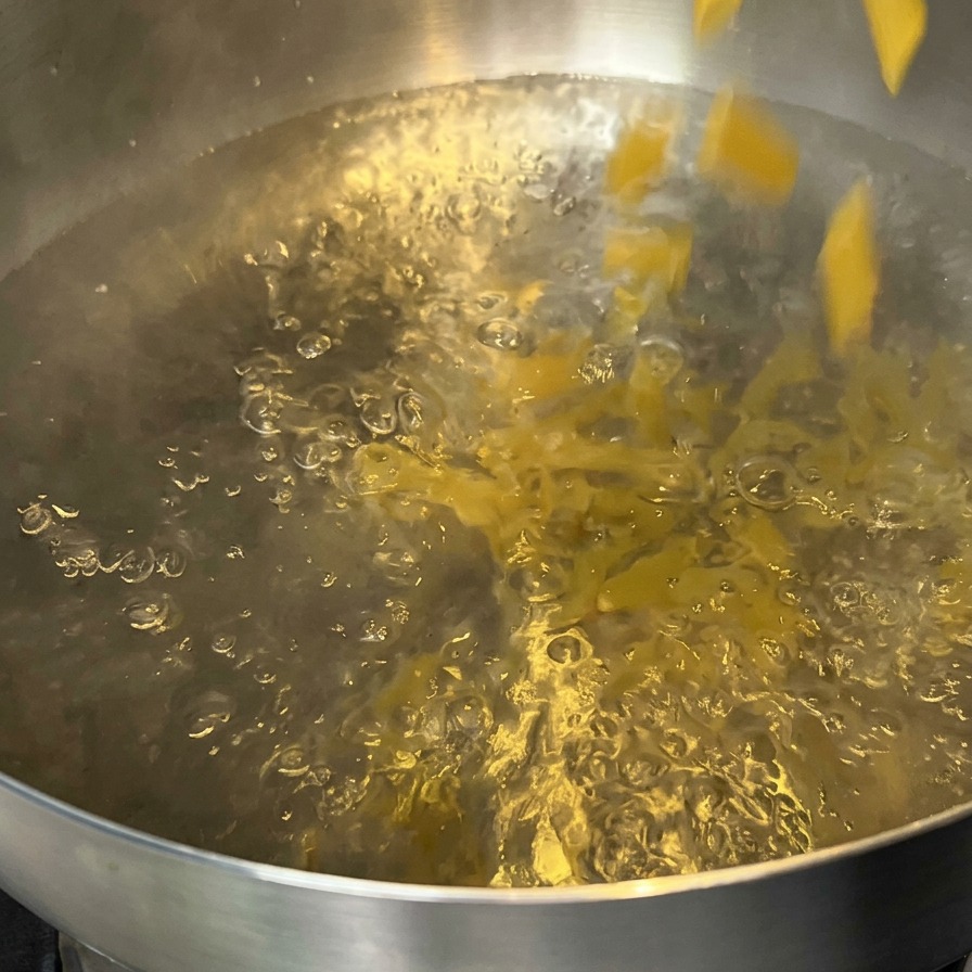 沸騰したお湯の入った鍋にペンネを入れている様子