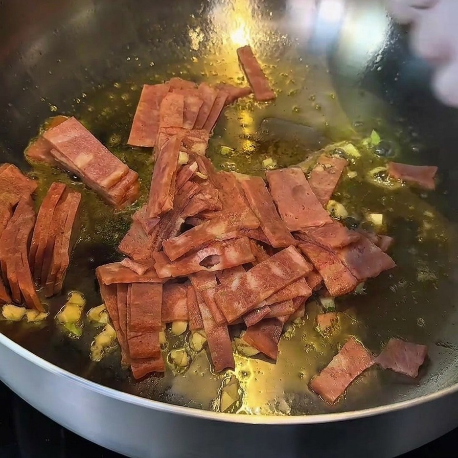 フライパンで炒められ、縁がこんがりと色づいたベーコンとにんにく