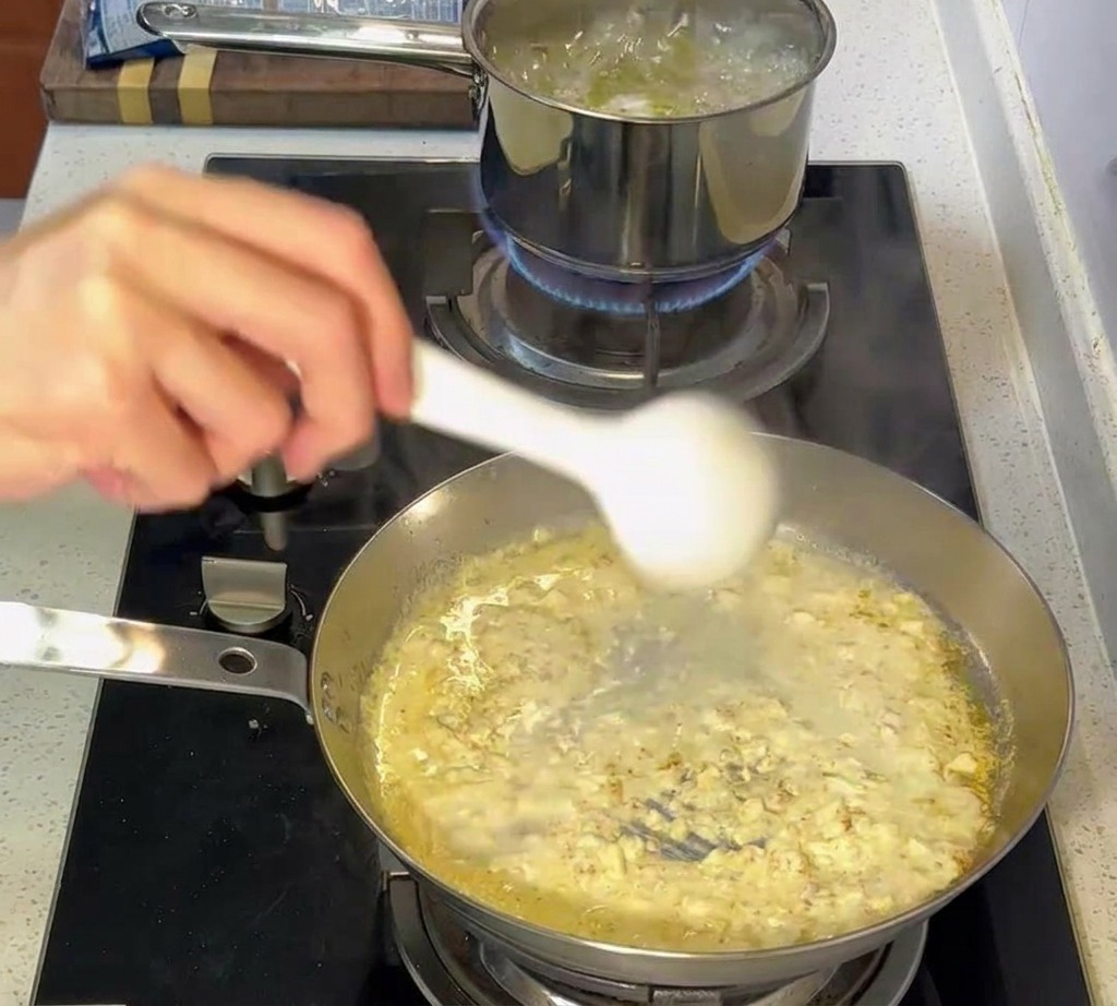 茹で上がったパスタをクリームソースに移す様子。