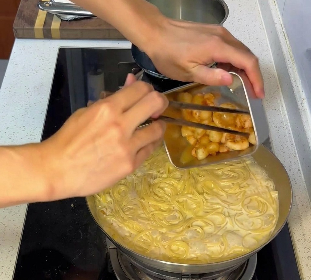 焼いておいたシーフードを仕上げのパスタに加える様子。