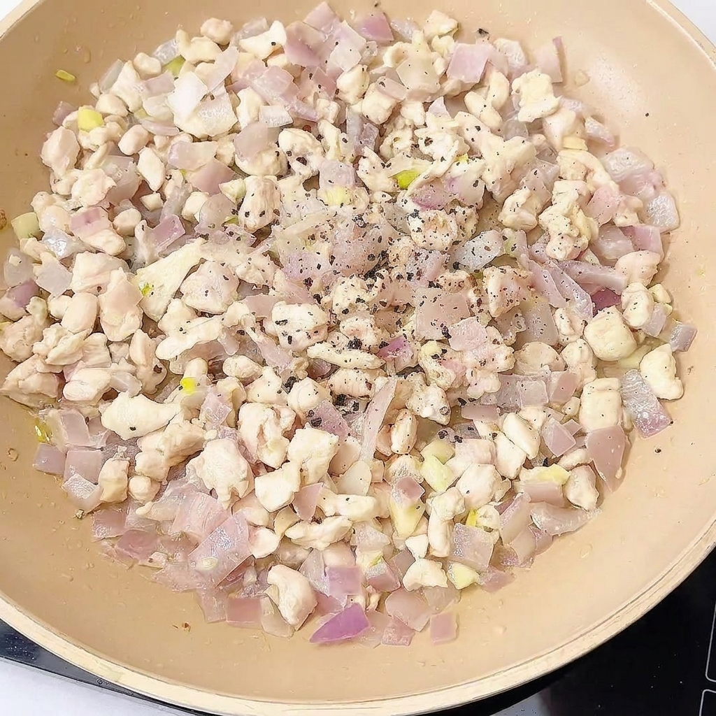 炒めた鶏肉に調味料を加えて和えている様子