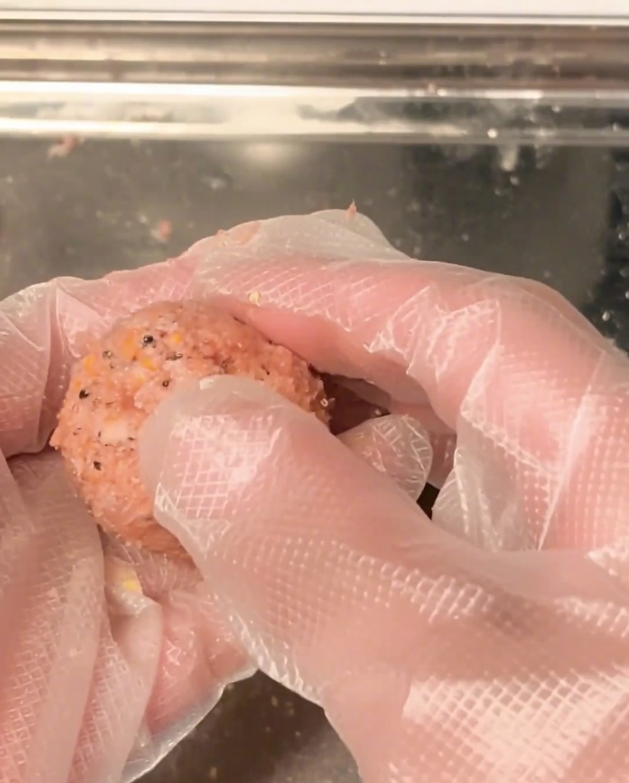 手でひき肉を丸く均一に成形している様子。