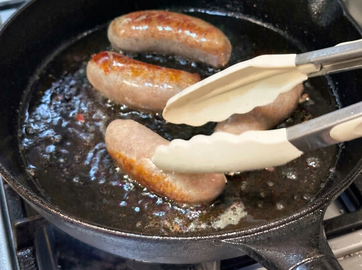 トングでソーセージをひっくり返しながら焼く様子。