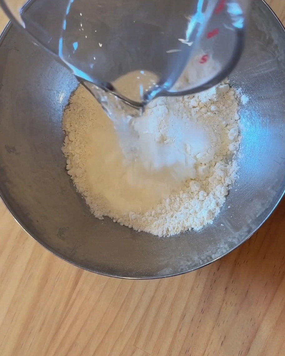 ボウルの中で小麦粉、水、酵母を混ぜ合わせてピザ生地を作る様子。