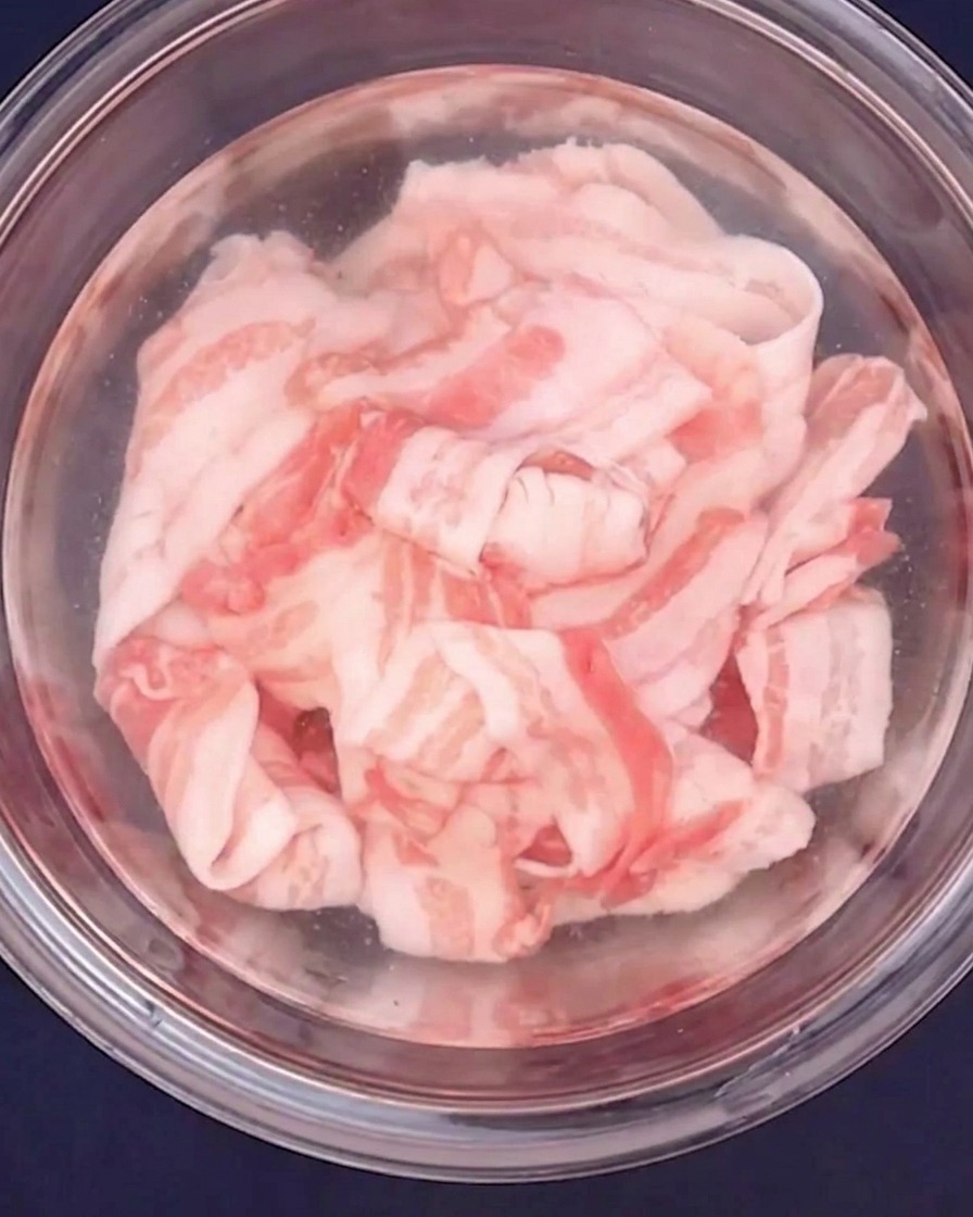 耐熱ボウルに入れた豚バラ肉にお湯をかけている様子。