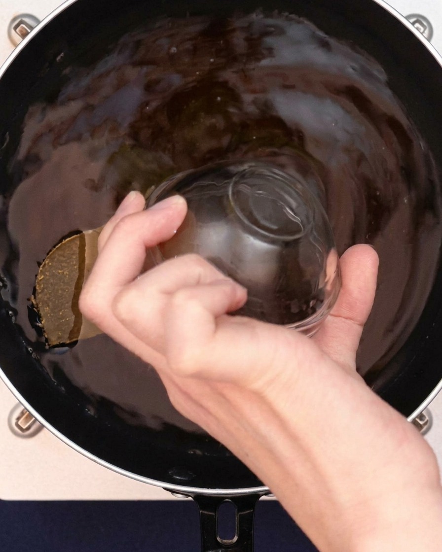 顆粒スープの素をカレーつゆに振り入れている様子。
