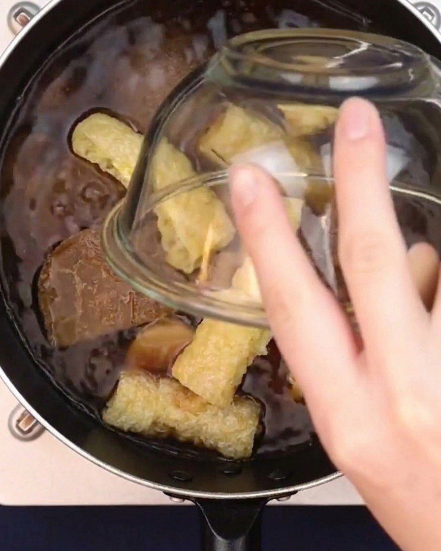 煮立たせたカレーつゆに油揚げを加えている様子。