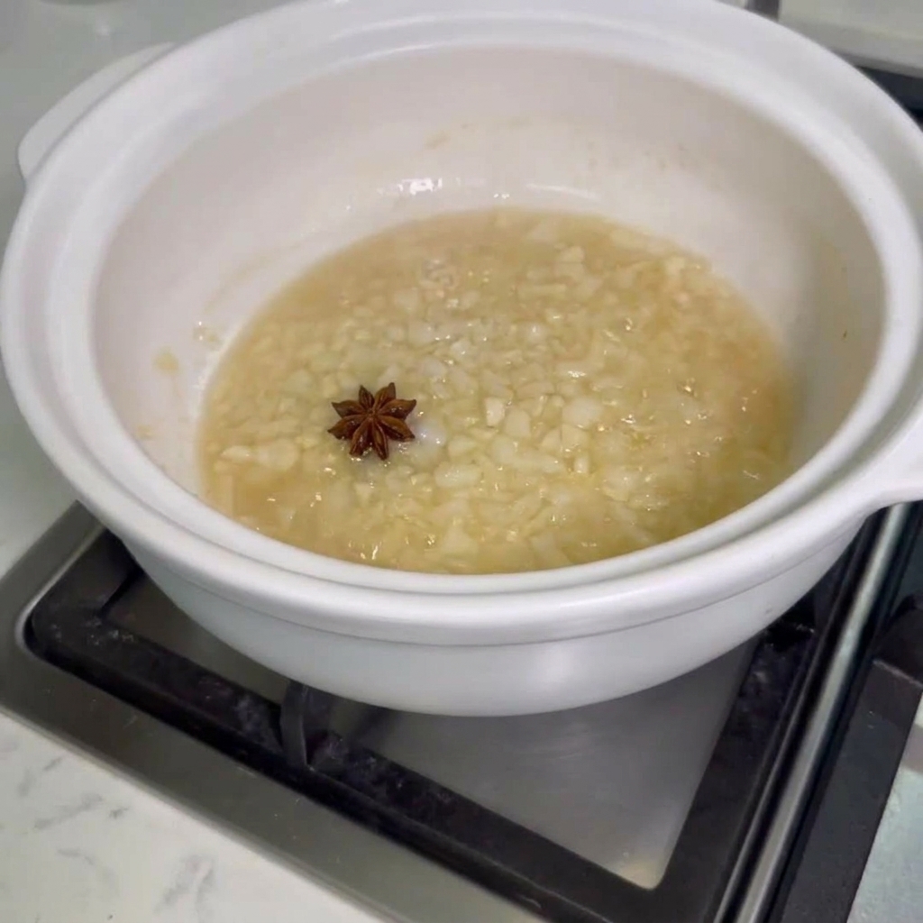 炒めた玉ねぎとにんにくが入った鍋に、八角と生の鶏手羽先を投入している様子。