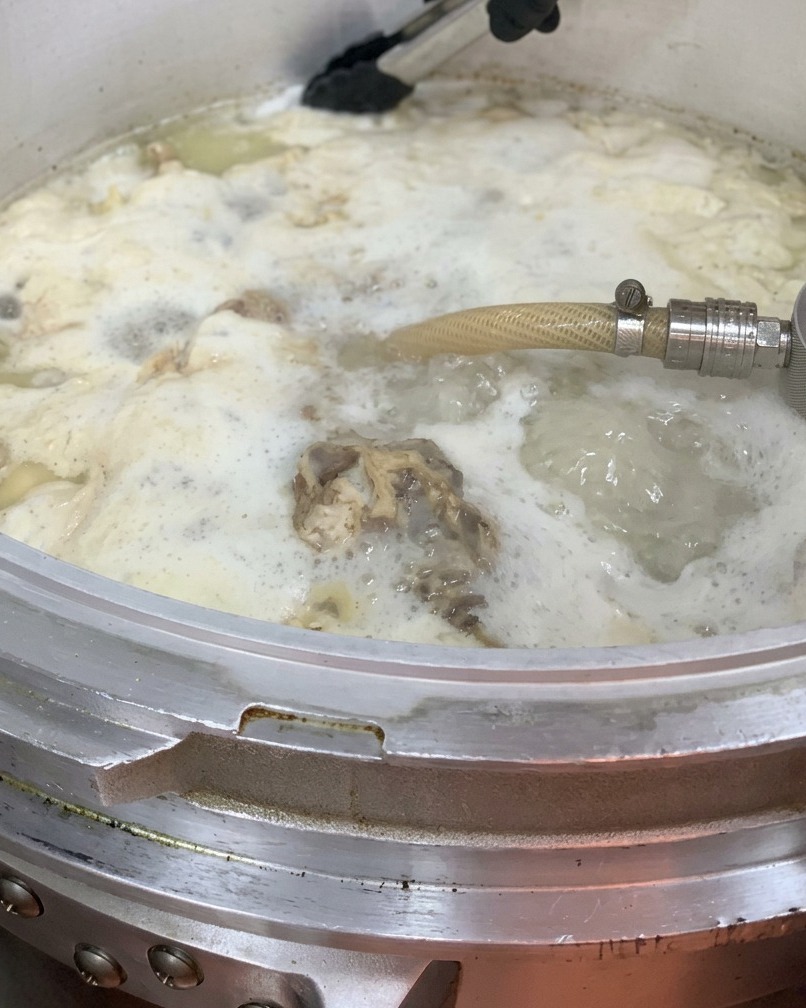 大きな鍋に鶏油を注ぎ入れている様子。