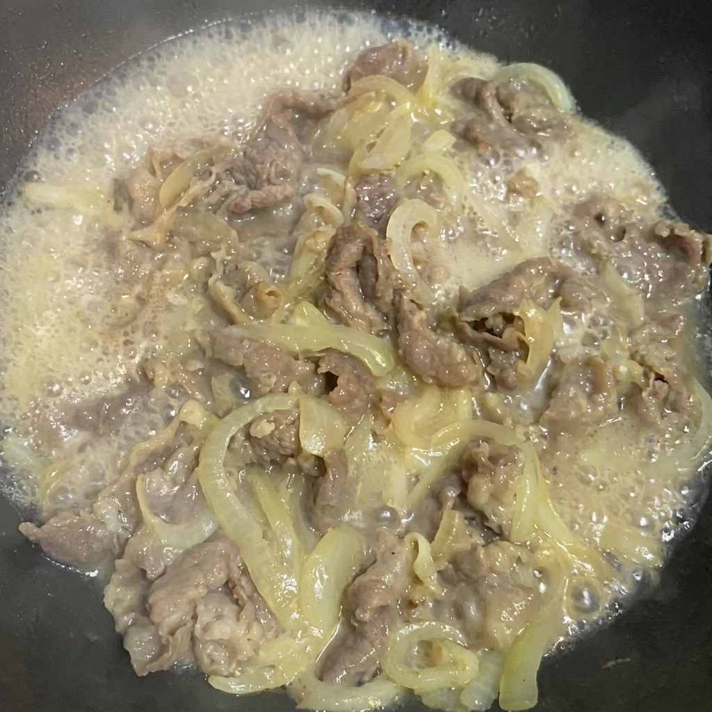 醤油、甘味料、塩で牛肉と玉ねぎを味付けしている様子。