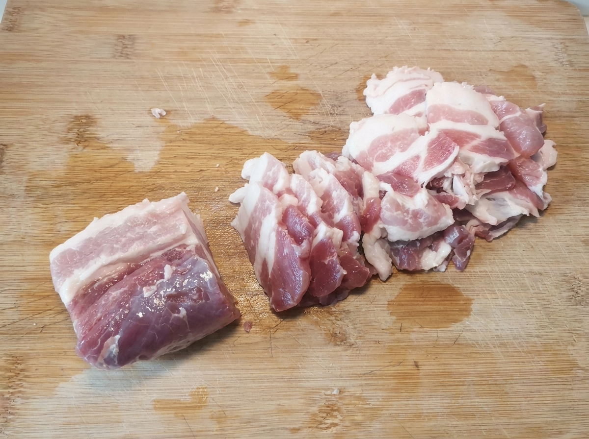 まな板の上にきれいに並べられた、生の薄切り豚バラ肉。
