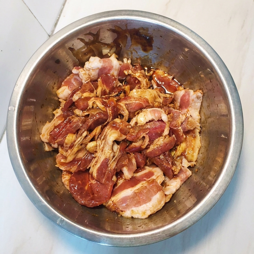 ボウルの中でタレと豚肉をしっかり混ぜ合わせている様子。