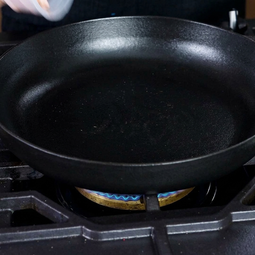 熱い鋳鉄製フライパンでカリカリに焼かれるダイス状のベーコン。