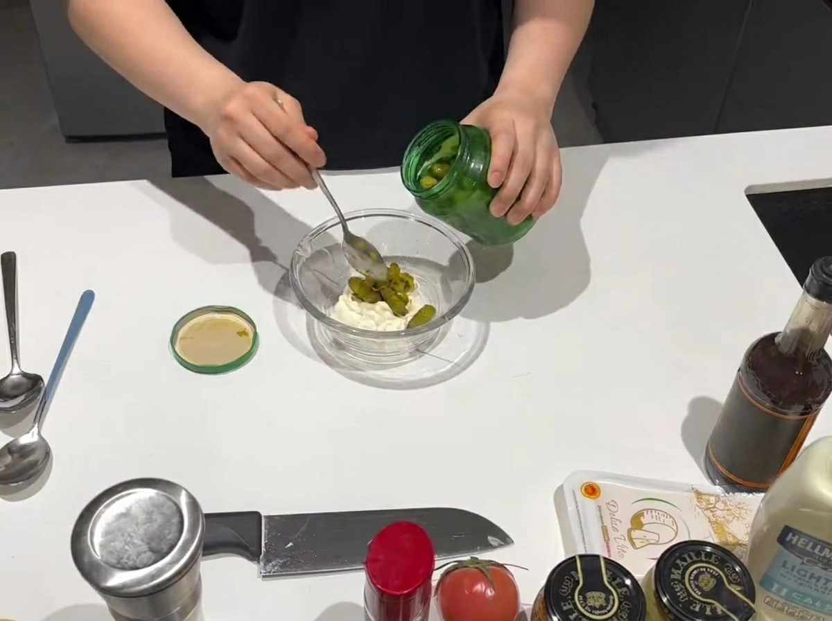 マヨネーズの入ったボウルにスプーンでスイートレリッシュを加えている様子。