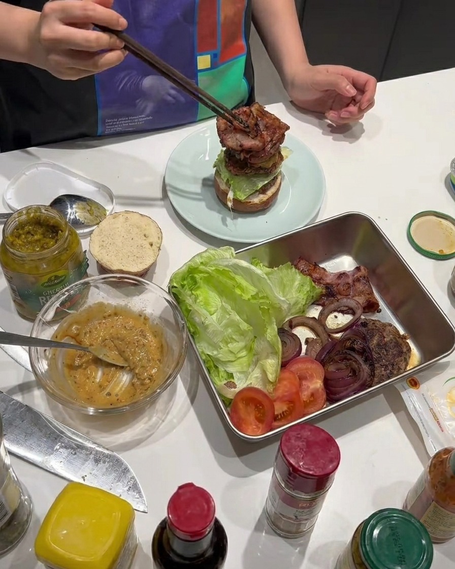 焼いたカリカリのベーコンの細切りをバーガーに加えている様子。