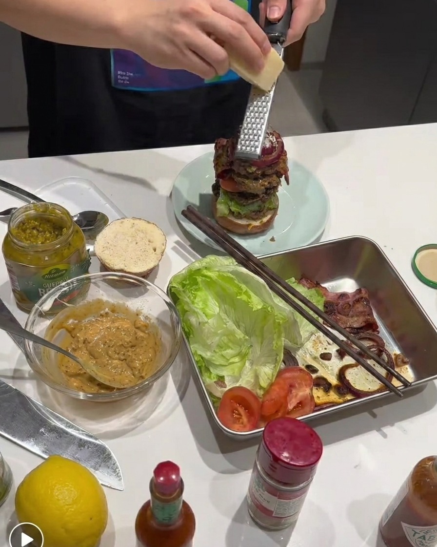 積み上げたバーガーの上に新鮮なパルメザンチーズを削りかけている様子。