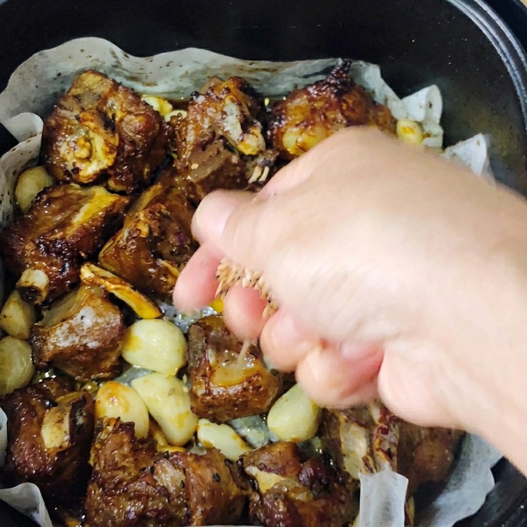きつね色に焼けたポークリブに、炒りごまと刻みネギを振りかけている様子。