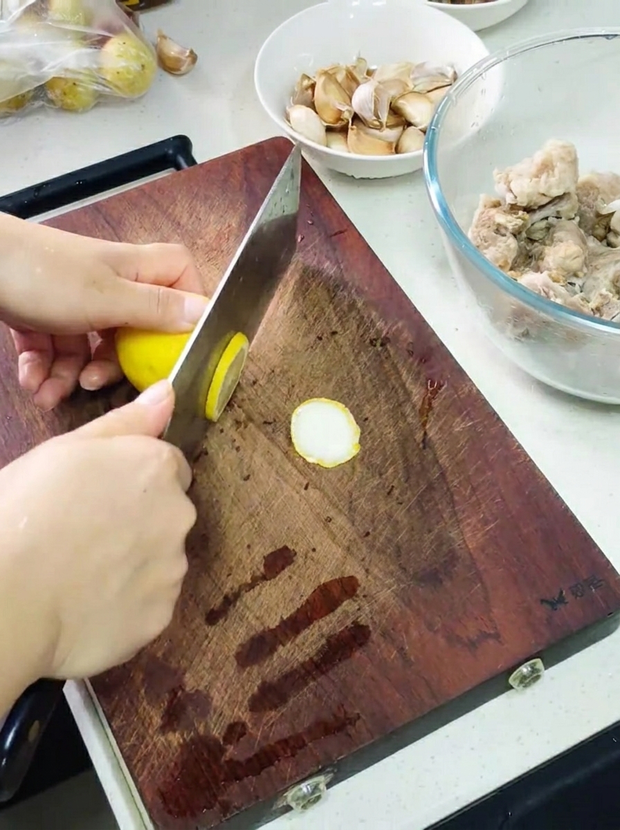 まな板の上でレモンを切り、マリネ液とニンニクが用意されたボウルの横に置かれている様子。