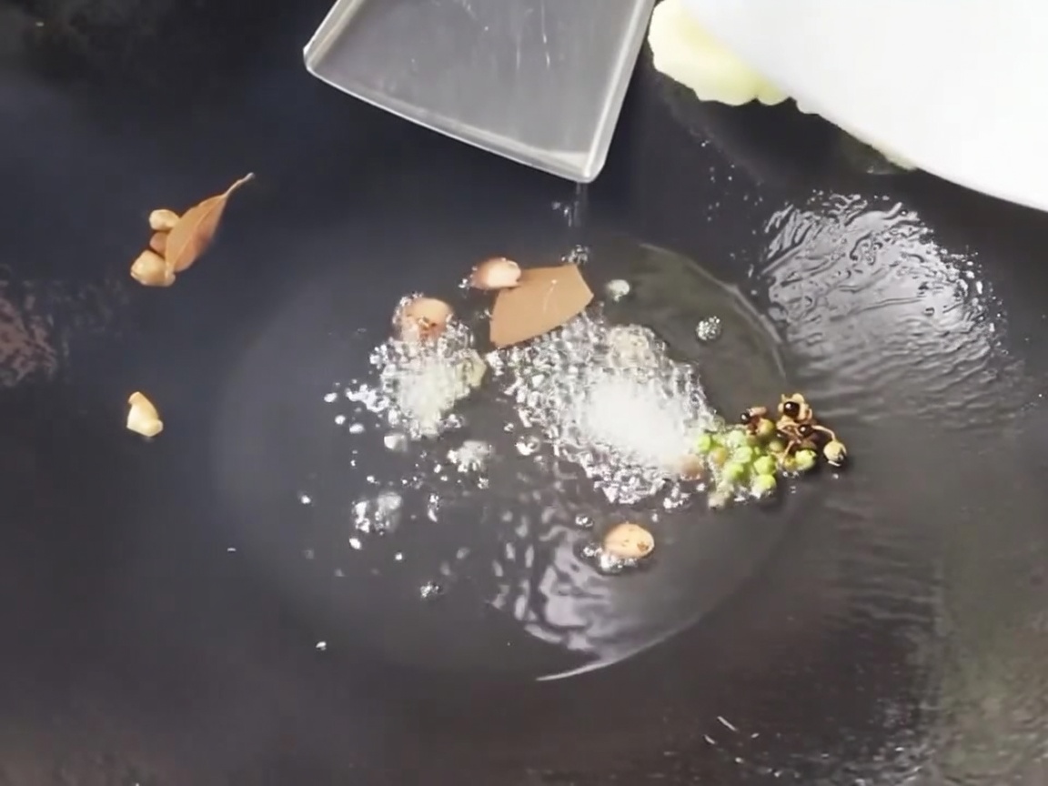 たけのことトウモロコシを鍋に入れて炒めている様子。