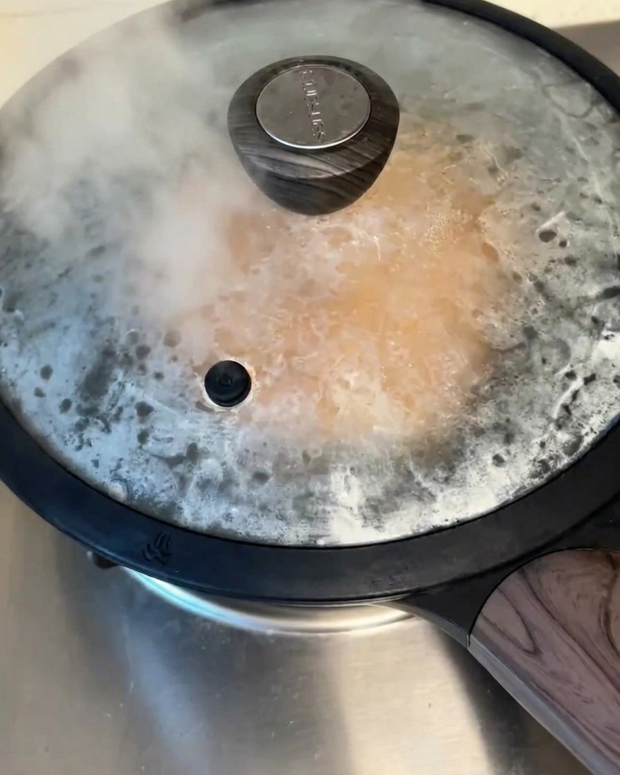 コンロの上の蓋をしたフライパン。隙間から湯気が出ている様子。