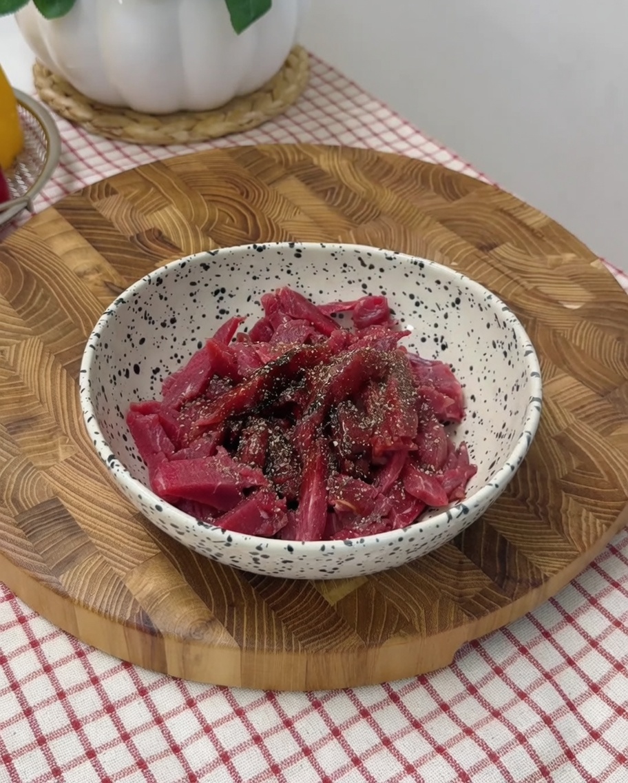 ボウルの中で味付けした牛肉を手で混ぜている様子。